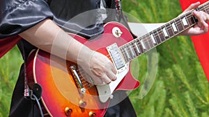 A musician in black gothic clothes plays the electric guitar.