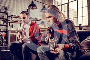 Musician with bob cut joining his friend playing the guitar