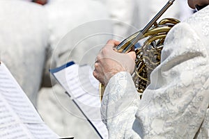 Musician of brass band plays french horn on street music fest