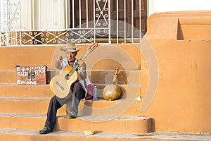 Guitar player calls to passers by in Trinidad, Cuba