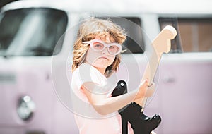 Musician child with a guitar. Joyful cute kid improvising. Happy kid enjoys music over colorful pink background.