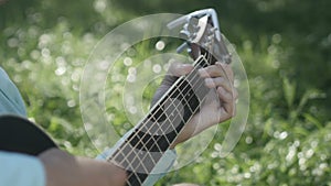 The musician clamps the chords on the guitar close-up