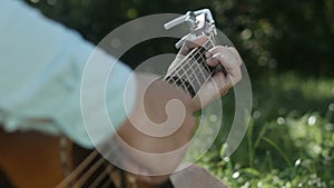 The musician clamps the chords on the guitar close-up