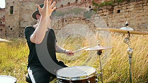 Musician drummer dressed in black clothes, hat, playing the drum set and cymbals