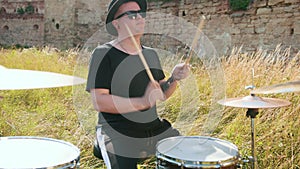 Musician drummer, playing drum set and cymbals, on street in sunny weather