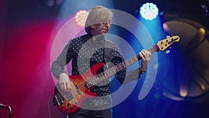 Musician with an electric guitar in his hands performs on stage of nightclub