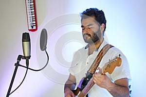 Musician with electric guitar playing music in studio