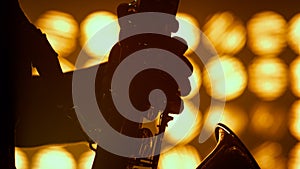 Musician hands playing saxophone jazz club closeup. Silhouette player hold sax.