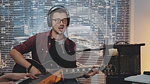 Musician in headphone and trendy casual clothes recording his new song in home studio