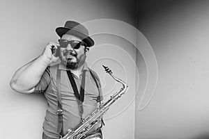 Musician with his saxophone, wearing his hat, in some places