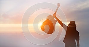 Musician holding acoustic guitar in hand of silhouette on sunset photo