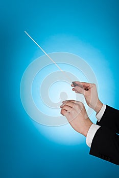 Musician Holding Baton Against Blue Background