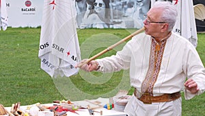 Musician man plying sopilka rebro ethnic woodwind musical instrument. Pan flute music festival Lviv, Ukraine May 14 2022