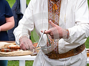Musician man plying triangle striking beater. Ukraininan idiophone metal ethnic musical instrument. Folk music festival photo