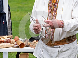 Musician man plying triangle striking beater. Ukraininan idiophone metal ethnic musical instrument. Folk music festival