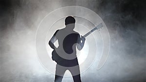 Musician man in a smoky studio masterfully plays bass guitar