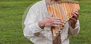 Musician man in vyshyvanka plying sopilka rebro ethnic woodwind musical instrument. Pan flute music festival in Ukraine