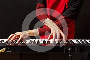 Musician play the keys of the electronic piano on black background