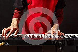 Musician play the keys of the electronic synth on black background