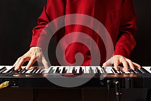 Musician play the keys of the electronic synthesizer on black background