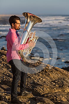 Musician play to musical instrument Tuba on romantic sea shore. Hobby.