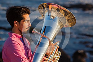 Musician play to Tuba on romantic sea shore. Relax.