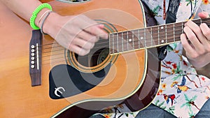 Musician playing on acoustic guitar. Close-up view fingers, colour bokeh. Rock, Blues, Jazz, Pop music style play on