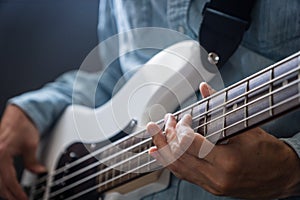 Musician playing bass guitar finger style in studio