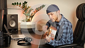 Musician playing chords on acoustic guitar. Stylish talented guitarist plays guitar, performs music composition. Young guy playing