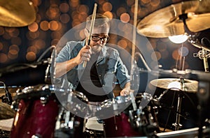 Musician playing drum kit at concert over lights