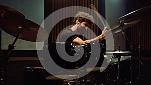 Musician playing on drum kit in recording studio. Drummer hitting drum cymbals.