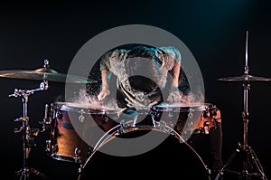 Musician playing drums with splashes, black background with beautiful soft light