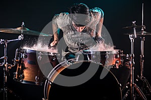 Musician playing drums with splashes, black background with beautiful soft light