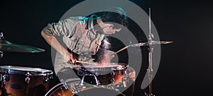 Musician playing drums with splashes, black background with beautiful soft light