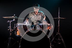 Musician playing drums with splashes, black background with beautiful soft light