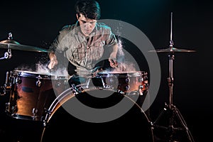 Musician playing drums with splashes, black background with beautiful soft light