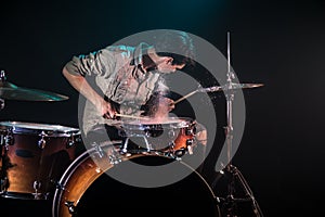 Musician playing drums with splashes, black background with beautiful soft light