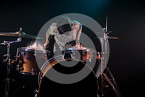 Musician playing drums with splashes, black background with beautiful soft light