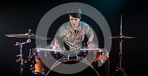 Musician playing drums with splashes, black background with beautiful soft light