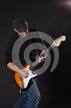 Musician playing electric guitar on dark background