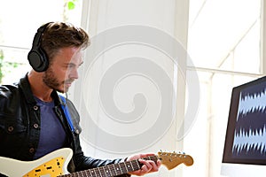 Musician playing electric guitar with headphones