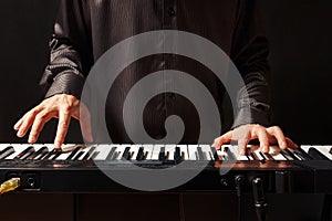 Musician playing the electronic organ on black background