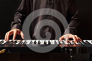 Musician playing the electronic synthesizer on black background