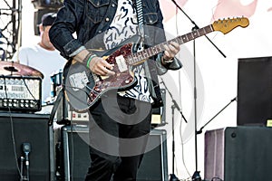 Musician playing guitar on outdoor stage during live concert