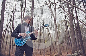 Musician playing guitar in the woods