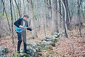 Musician playing guitar in the woods