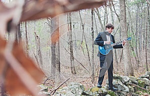 Musician playing guitar in the woods