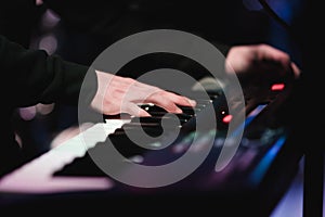 Musician playing on the keyboard synthesizer piano keys. Musician plays a musical instrument on the concert stage