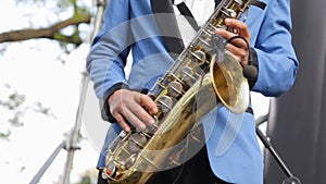 Musician playing saxophone close-up. Wireless microphone saxophone. Man fingers pressing keys of the musical instrument