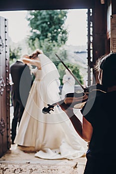 Musician playing on violin while beautiful bride and groom standing in church after wedding matrimony. Elegant string quartet